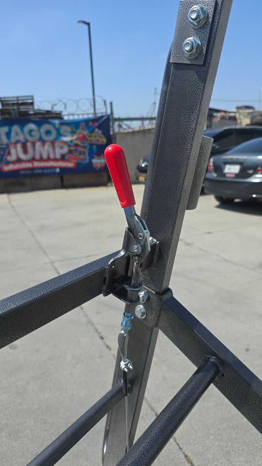 Close-up of the manual brake lever on the Monster Dolly, showcasing its sturdy metal frame and mechanism in a parking lot